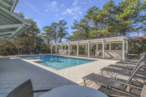 A pool area with lounge chairs and a covered seating area.