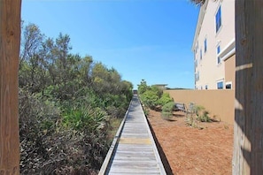 A wooden boardwalk leading to a building with multiple windows. - Beach Chairs, Bikes & Across From Beach! ~ Seas The Day in Magnolia Cottages on 30A (Seacrest Beach)