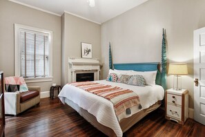 A bedroom with a large bed, a fireplace, a chair, and a nightstand with a lamp. - Porch Lovers Dream: 2 King Beds, Free Easy Parking (Savannah)