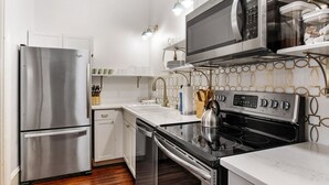 A compact kitchen with stainless steel appliances, a microwave, and a stove.