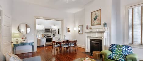 A spacious living room with a fireplace, a dining area, and a kitchen in the background.