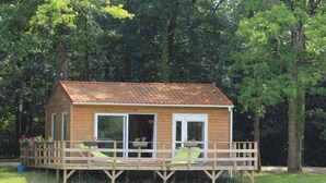 A wooden cabin with a deck, large windows, and outdoor seating. - Les chalets de la héronnière (Chef-Boutonne)
