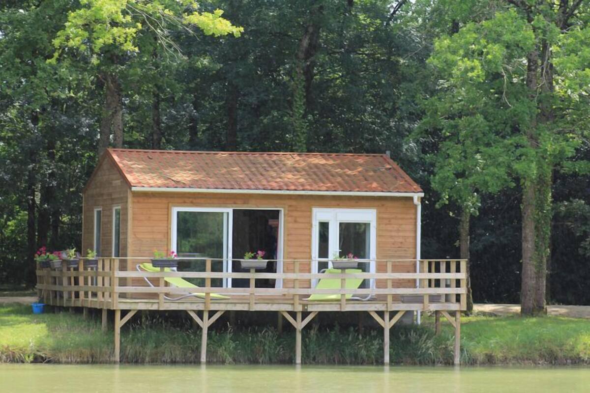 A wooden cabin with a deck, large windows, and outdoor seating.
