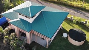 A large house with a green roof and a small garden. - Nice, Big House near Kehena/ Pohoiki Black Sand Beaches and Lava Fields. (Pahoa/Kalapana-Seaview)