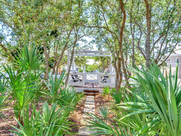 A pathway leading to a white gazebo surrounded by lush greenery and trees.