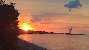 Un atardecer sobre un cuerpo de agua tranquilo con una estructura distante en el horizonte.