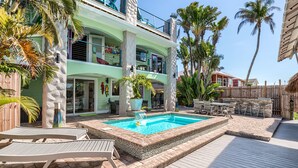 Un bâtiment à deux étages doté d’une piscine, de mobilier d’extérieur et de palmiers.