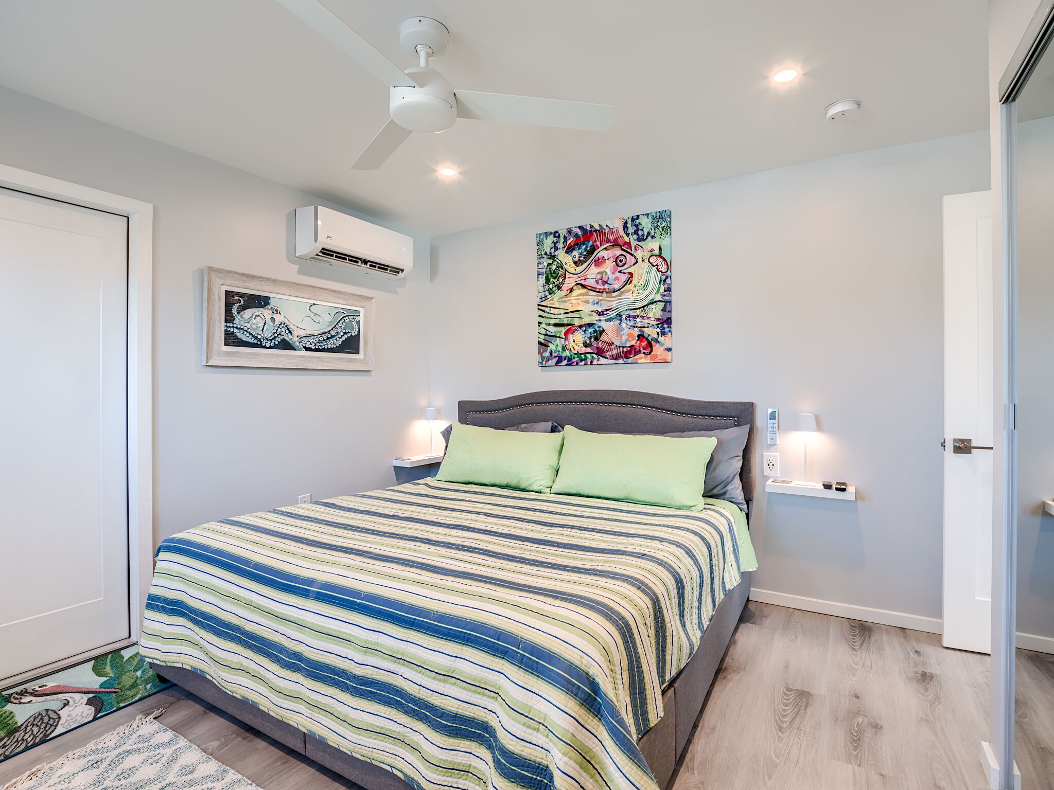 Un dormitorio con una cama, un ventilador de techo, aire acondicionado y dos lámparas fijadas a la pared.
