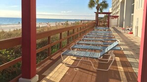 A beachside balcony with sun loungers, a wooden railing, and a view of the beach and ocean. - 4th floor@Majestic! 3br!2 King beds+Triple Bunk! Gym/weight room access included (Panama City Beach)