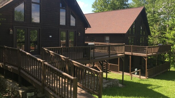 A wooden cabin with a deck, large windows, and a brick roof. - Perfect family space. Lots of room. Easy drive to New River Gorge National Park. (Ghent)