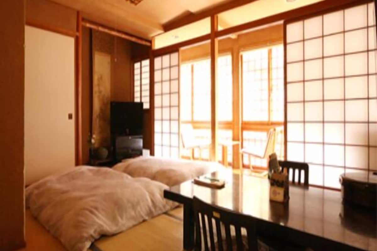 Ein traditioneller japanischer Raum mit Tatami-Bodenbelag, einem niedrigen Tisch und Schiebetüren.