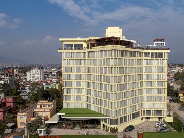 A multi-story hotel with a flat roof, large windows, and a green lawn area. - Vivanta Kathmandu (Lalitpur)