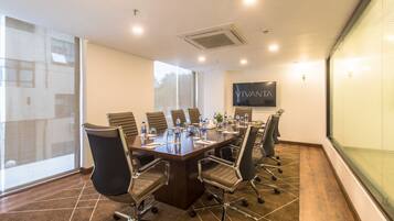A conference room with a long table, chairs, a flat-screen TV, and a large window.