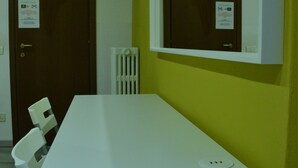 A room with a white desk, a chair, a door, and a window with a mirror. - Leonardo Tourist House (Florence)