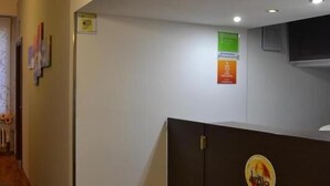A reception area with a wooden floor, a reception desk, and a wall with framed certificates. - Leonardo Tourist House (Florence)