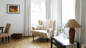 Una sala de estar con un sillón a rayas, una mesa con lámpara y un cuadro en la pared.