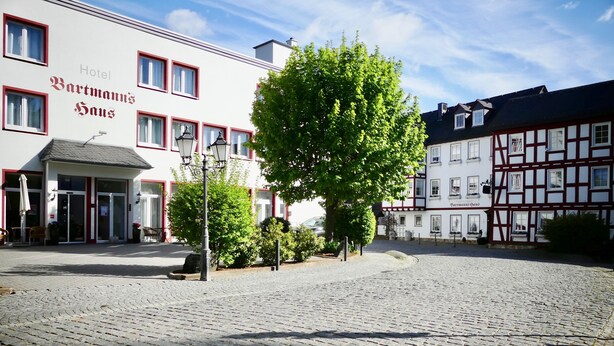 Una plaza adoquinada con un edificio tradicional europeo que dice "Hotel Bartmanns Haus".