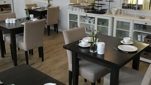 Comedor con mesas dispuestas para dos, con platos blancos, tazas y cubiertos.