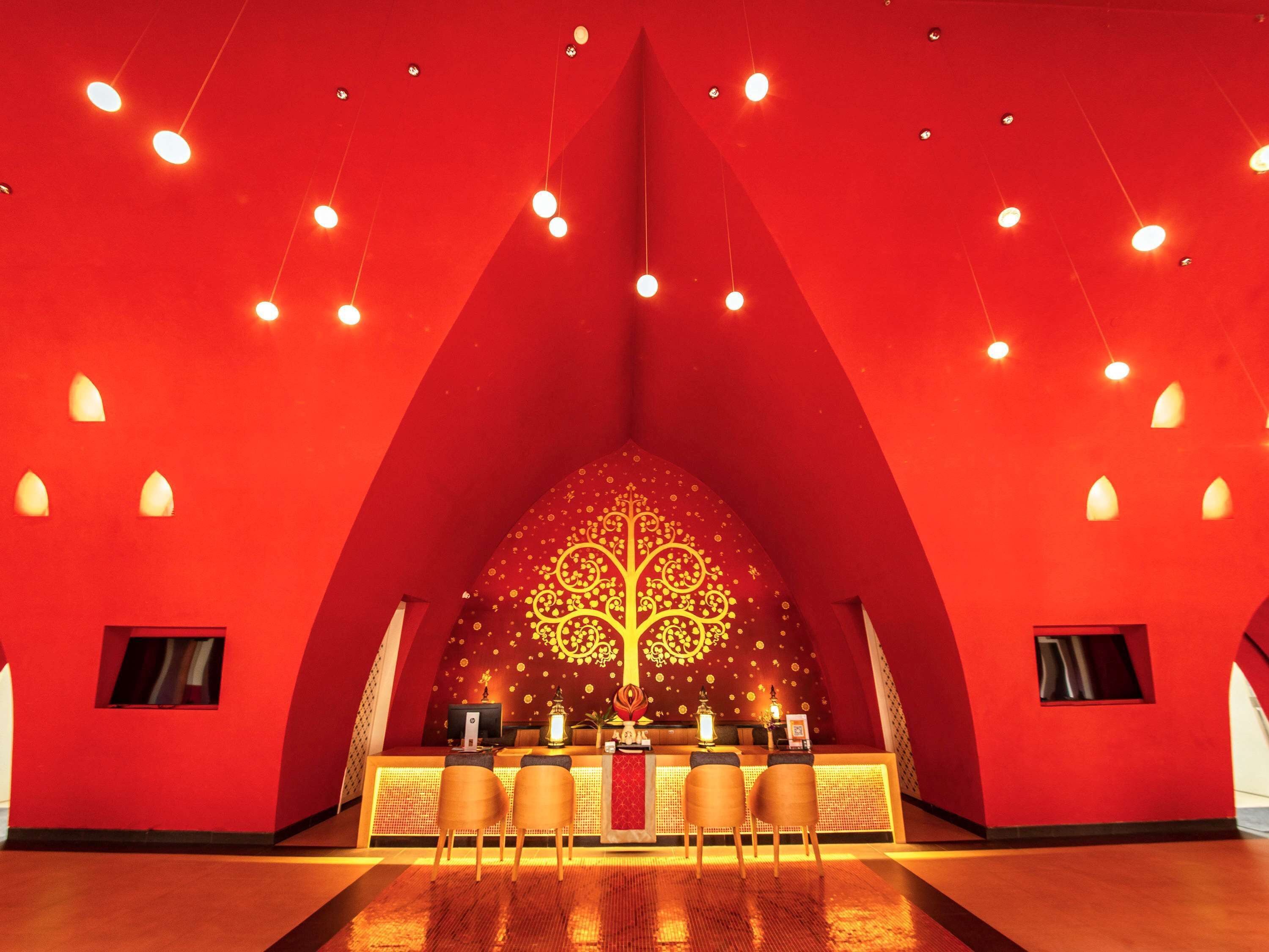 A reception area with a red interior, a decorative tree design on the wall, and two reception desks with chairs.