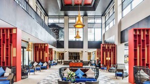 Eine geräumige Lobby mit hohen Decken, modernen Möbeln und einer zentralen Sitzecke.