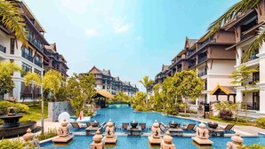 Ein Resort mit einem zentralen Pool, umgeben von Liegebereichen und mehrstöckigen Gebäuden mit Balkonen.