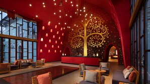 Eine geräumige Lobby mit einer rot und gold verzierten Wand, gemütlichen Sitzbereichen und einem Empfangstisch.