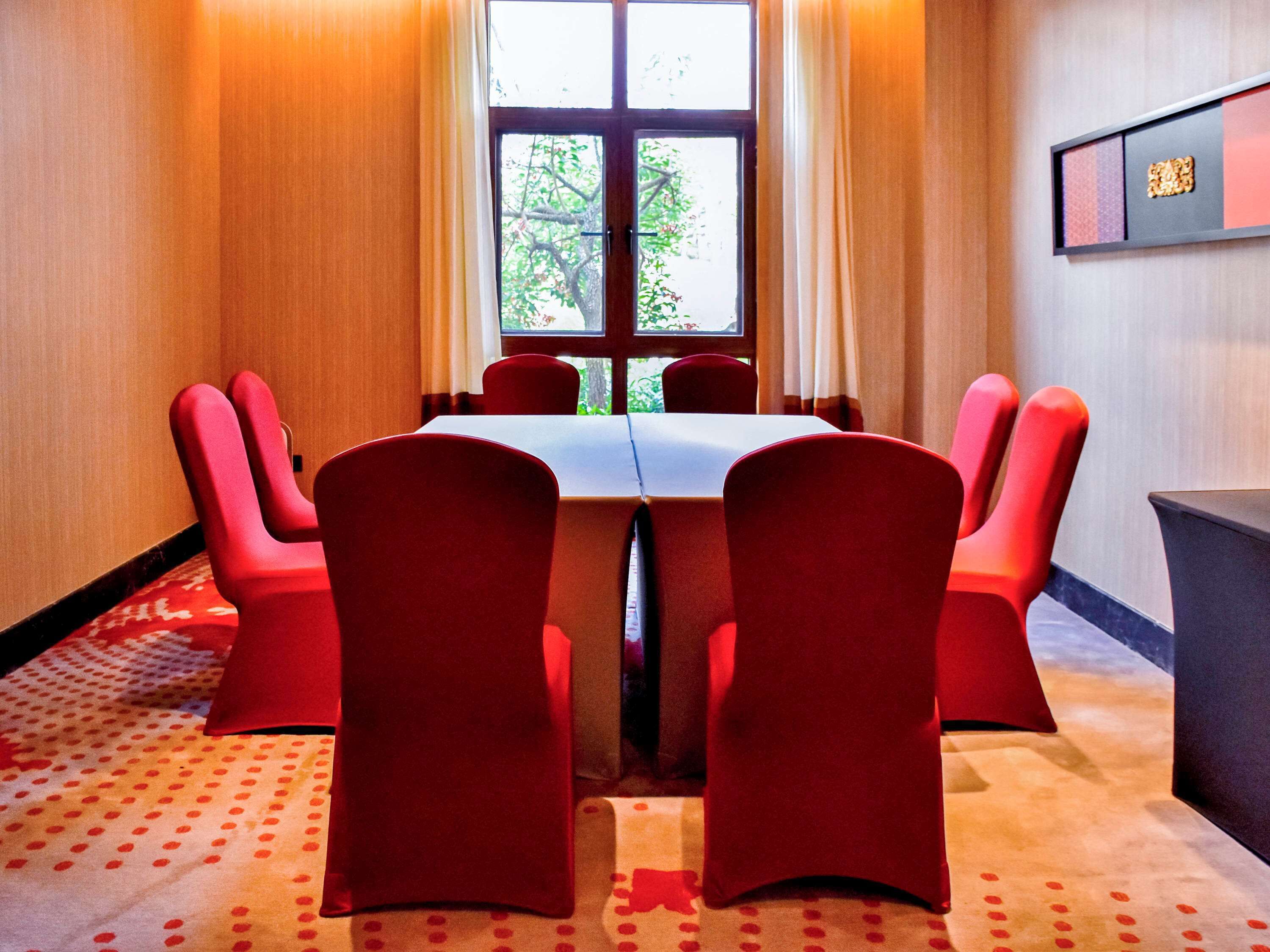 A conference room with a large table and six red chairs.
