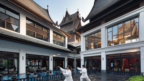 Ein Innenhof mit traditioneller Architektur, einem Pool und zwei Personen, die Kampfsport betreiben.