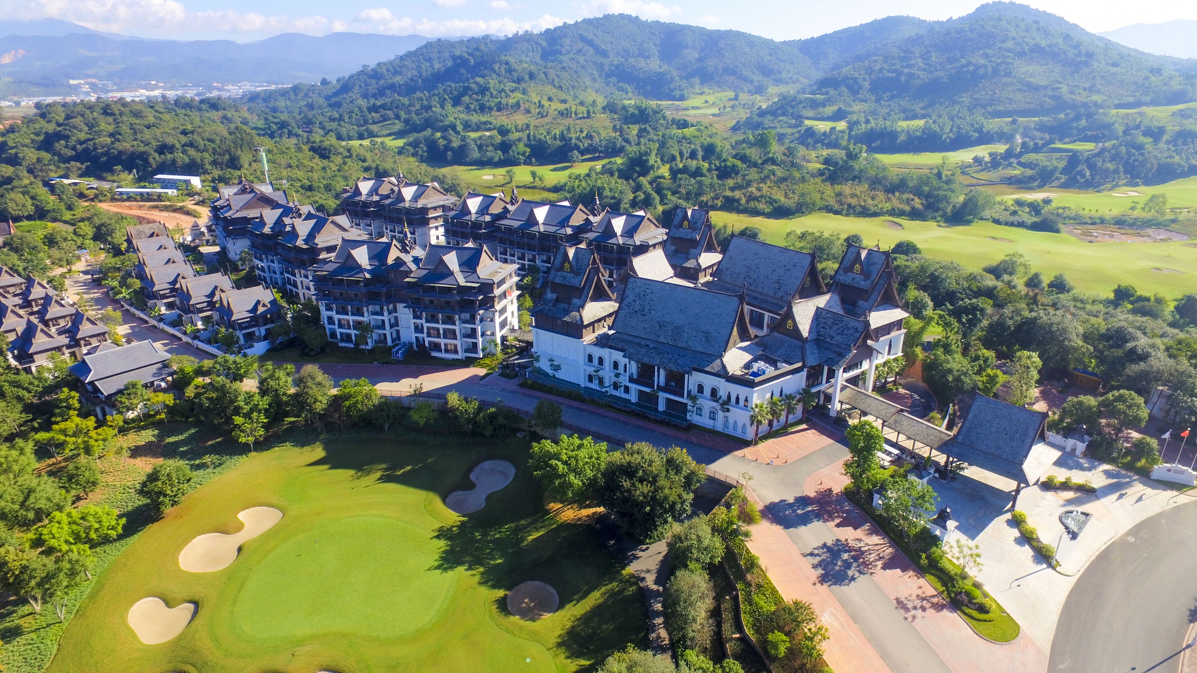 An aerial view of a resort with multiple buildings, a golf course, and surrounding greenery.