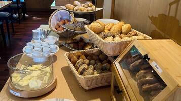 Ein reichhaltiges Buffet mit verschiedenen Speisen, darunter Brot, Gebäck und eine Butterplatte.