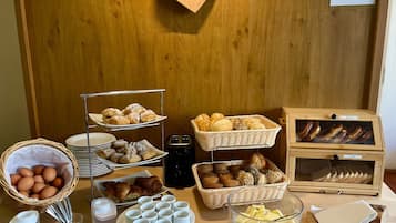 Un bufé de desayuno con pan, bollería, huevos y mantequilla.