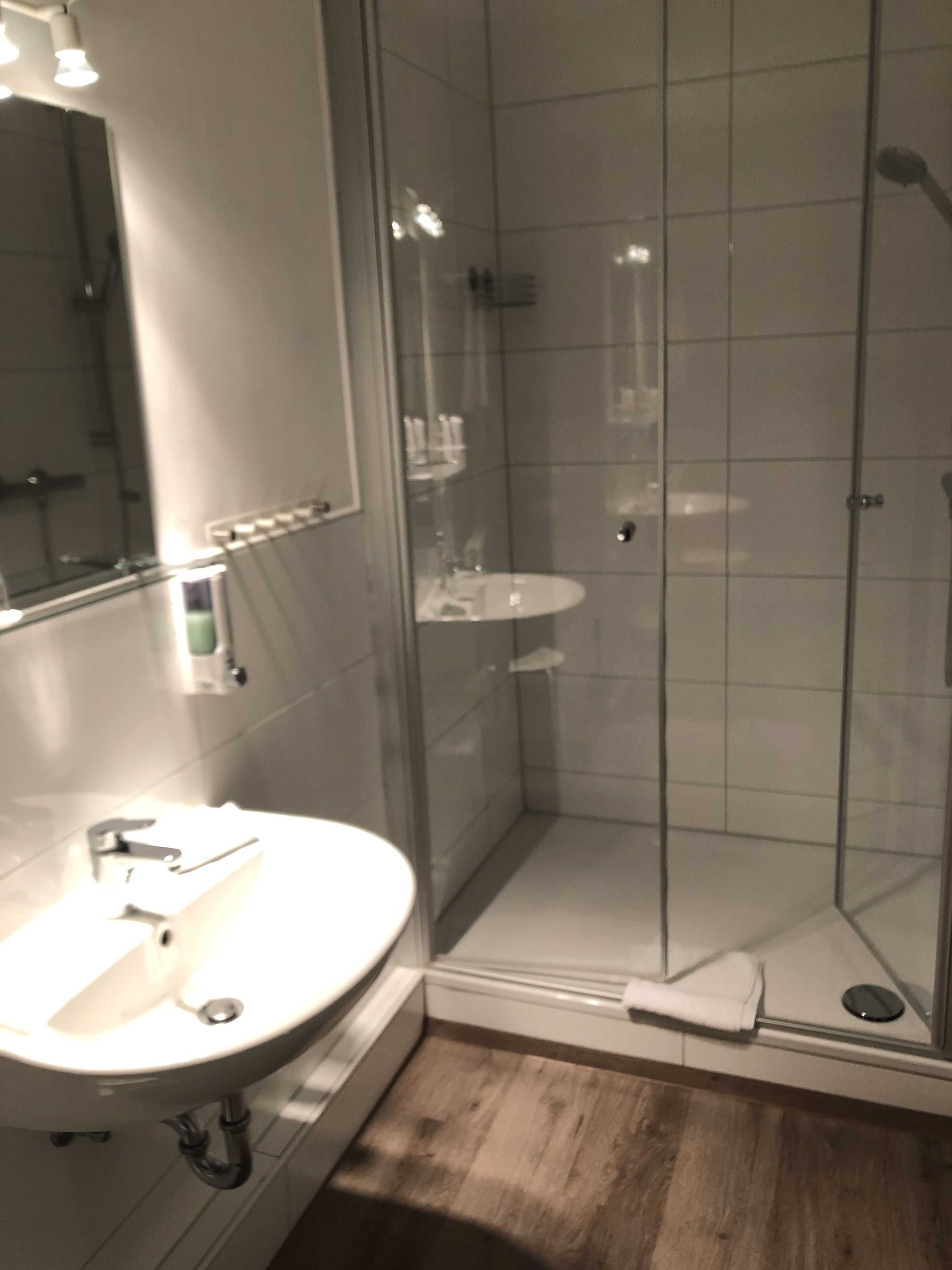 Un baño moderno con ducha de vidrio, lavamanos y espejo.
