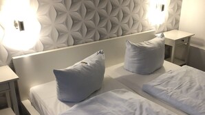 A hotel room with a modern design, featuring a large bed with two pillows, a bedside table, and a wall with a geometric pattern. - Gasthaus Zum Schwan (Dillenburg)