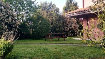 Eine Rasenfläche mit einer Holzbank und einem Gebäude mit einem Ziegeldach.