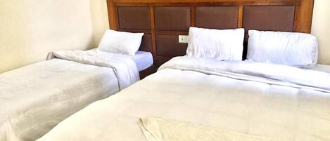 Una habitación de hotel con dos camas individuales, cada una con ropa blanca y cabeceros de madera.