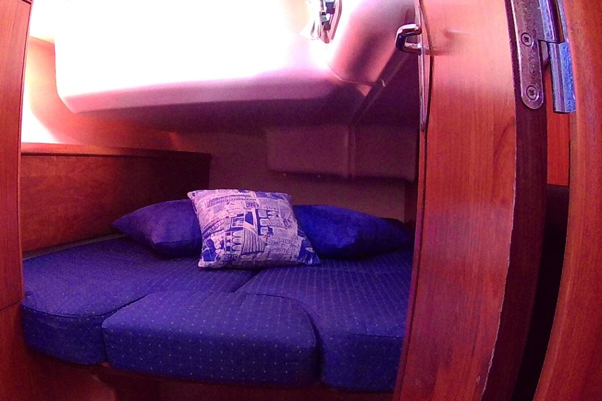 Une petite cabane avec un lit simple, un oreiller et une porte en bois.