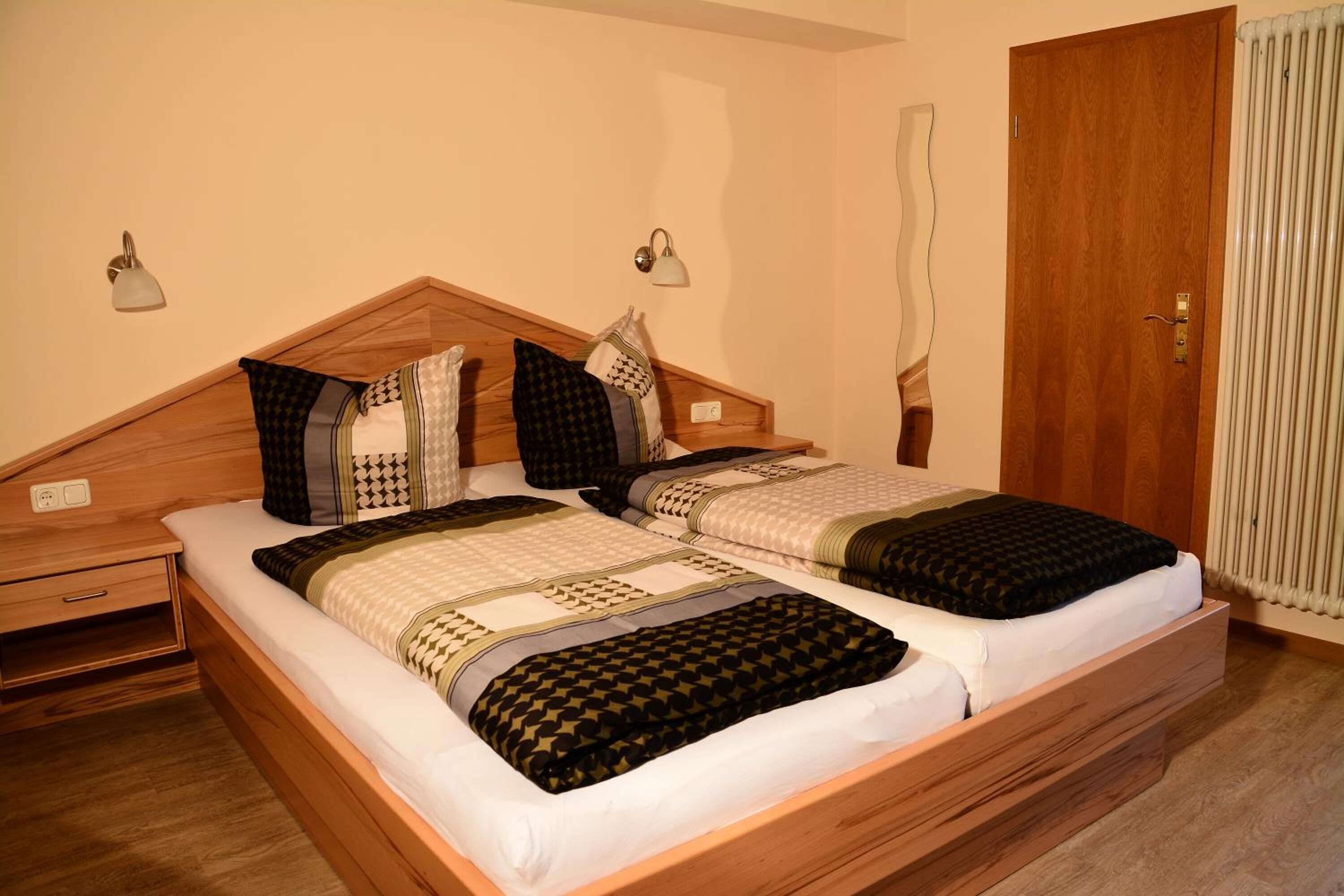Una cama doble con cabecera de madera, dos mesitas de noche y un aparador.