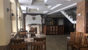 Una àmplia zona de menjador amb taules i cadires de fusta, una llar de foc i una escala que condueix a un nivell superior.