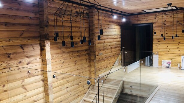 Un interior de fusta amb una escala de vidre, parets de fusta i lluminàries penjants.