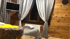 Habitació acollidora amb un llit, una taula petita i una finestra amb cortines.