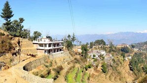 A hillside village with a prominent building featuring a balcony, surrounded by mountainous terrain and sparse vegetation. - Hotel Taj Himalaya khirsu (Srinagar)