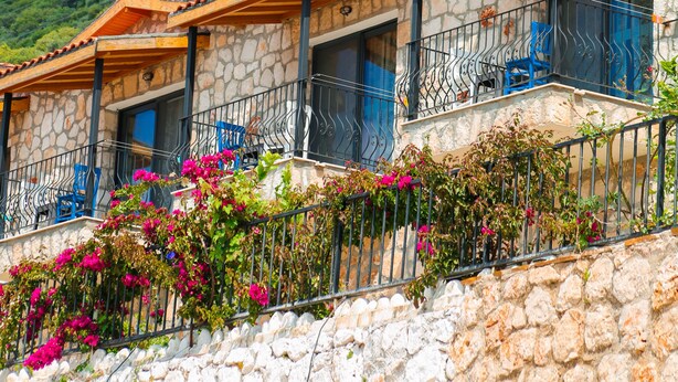 A row of stone buildings with balconies, set against a mountainous backdrop. - Kaskoy Hotel (Kas)