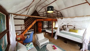 A cozy, rustic room with a bed, two chairs, a small table, and a staircase. - Swara Acacia Lodge (Athi River)