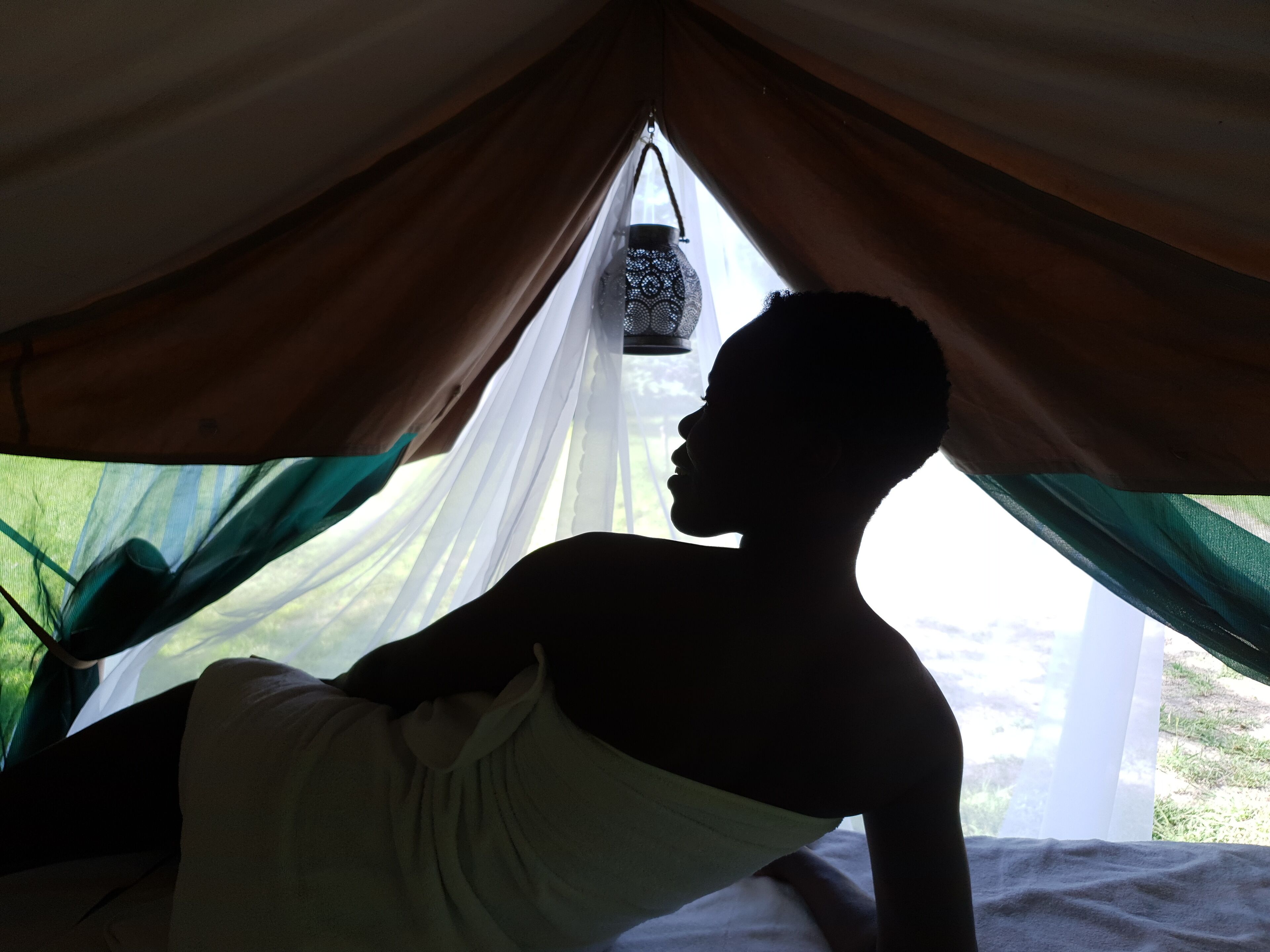 Una carpa con un farol colgante, una cama y vistas del exterior.