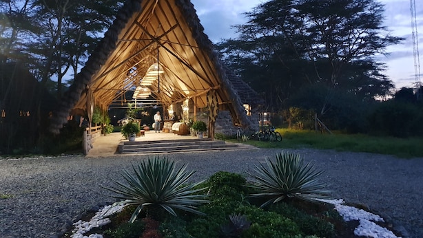 A thatched-roof structure with a central seating area, surrounded by potted plants and a gravel path. - Swara Acacia Lodge (Athi River)