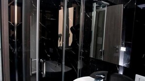 A modern bathroom with a glass shower enclosure, a white sink, and a large mirror. - Amazing Napoli (Naples)