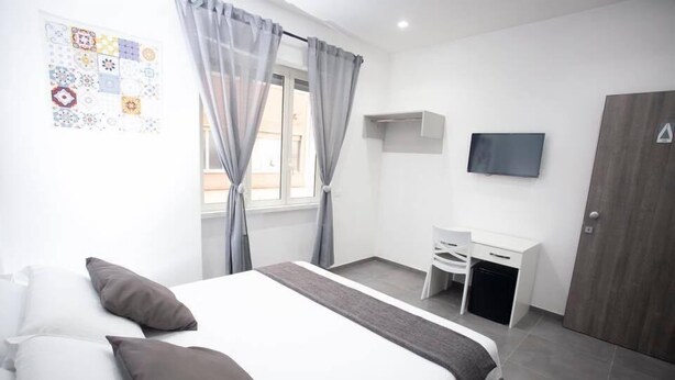 A modern hotel room with a bed, a desk, and a TV. - Amazing Napoli (Naples)
