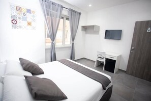 A modern hotel room with a bed, a desk, and a TV. - Amazing Napoli (Naples)