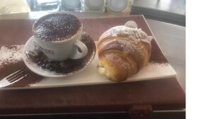 A croissant and a cup of coffee on a tray. - Amazing Napoli (Naples)