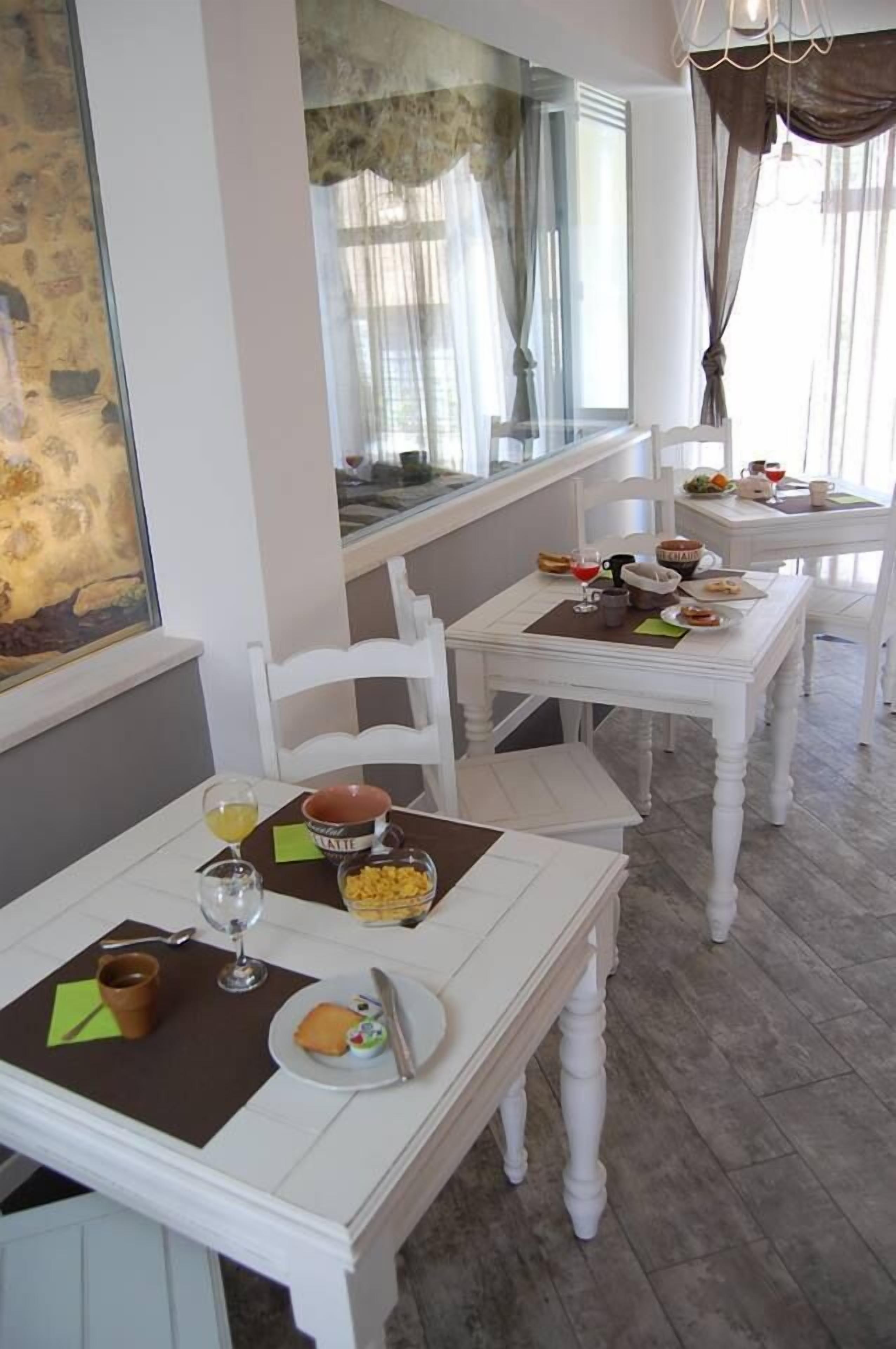 A dining area with white tables and chairs, breakfast items, and a view of the outdoors.